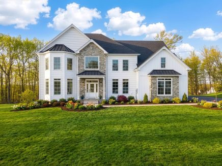 Two-story white and stone home with landscaped lawn and flower beds at 12 Pumpkin Grove in Southington, CT
