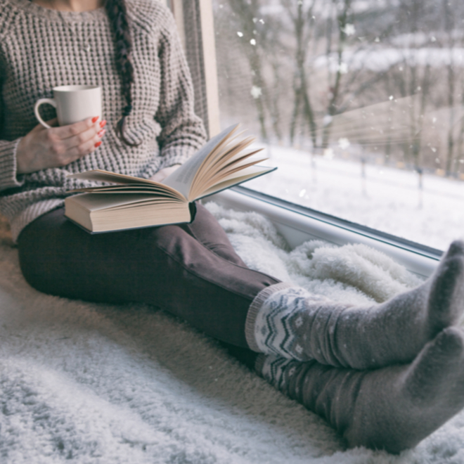 woman sitting by window during snowfall